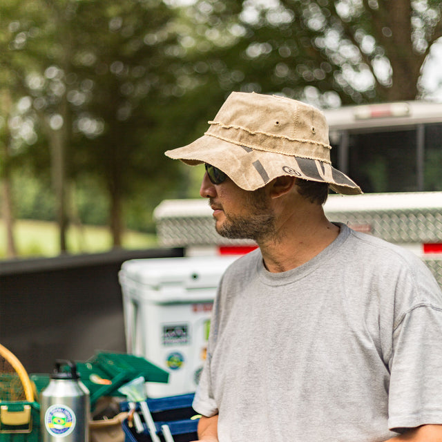 Man wearing a Real Deal Brazil original hat while standing in a forest, featuring a rugged outdoor style suitable for sun protection and adventure wear.