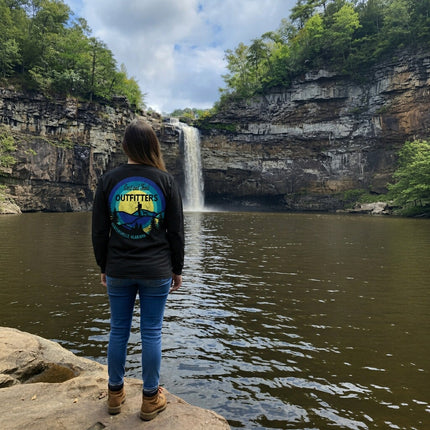 Women standing on rock in front of a waterfall with a custom shirt of Cast and Trail Outfitters and Guntersville Alabama on shirt.
