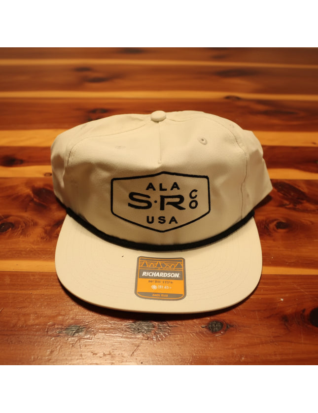 A cream-colored snapback cap with a black embroidered shield logo for Stealth Rod Co.