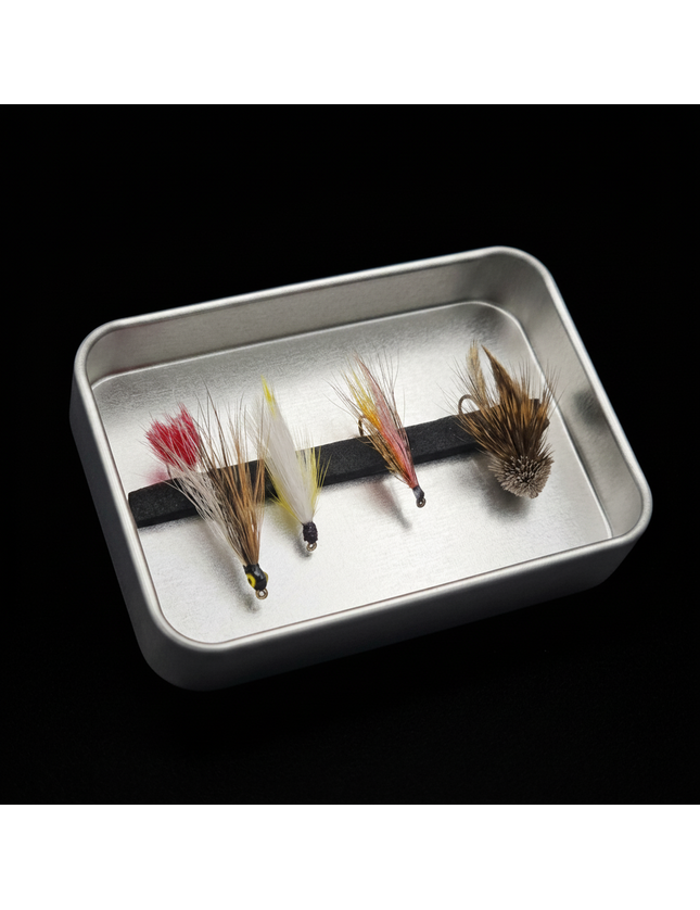 Four fly fishing flies on a metal tray against a black background
