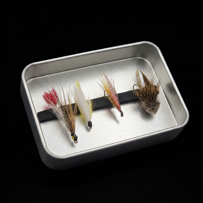 Four fly fishing flies on a metal tray against a black background