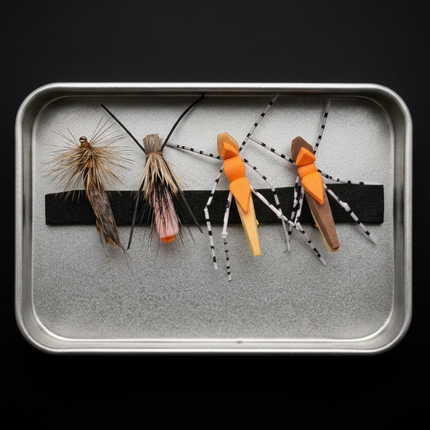 Set of fly fishing flies on a metal tray against a black background