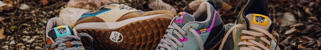Three pairs of Lems Trailhead shoes in different colors on a rocky, leafy ground