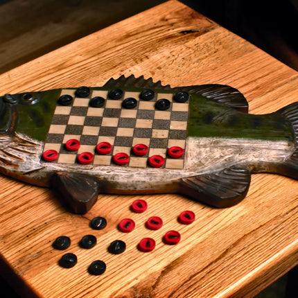 Wooden fish-shaped checkers board with checkers on a wooden surface
