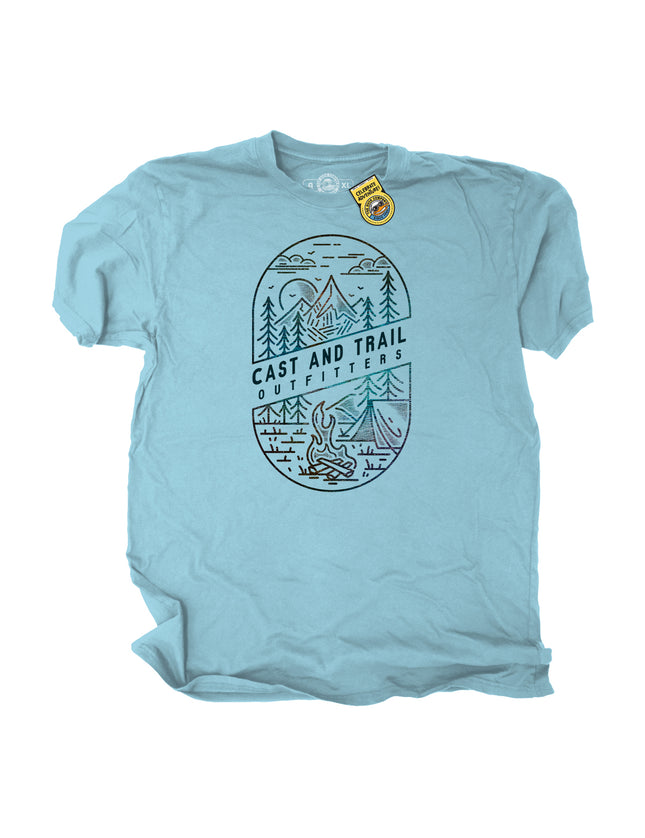 Light blue t-shirt with a graphic of mountains, trees, a tent, and a campfire with words Cast and Trail Outfitters.