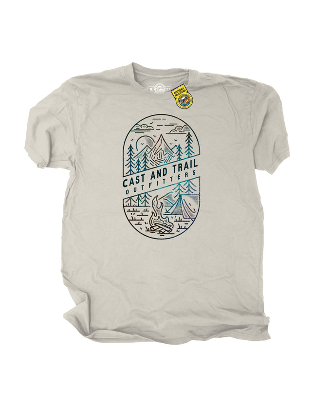 Beige t-shirt with outdoor graphic design of a forest, fire, tent, moon, campsite, and 'Cast and Trail Outfitters' text on a white background