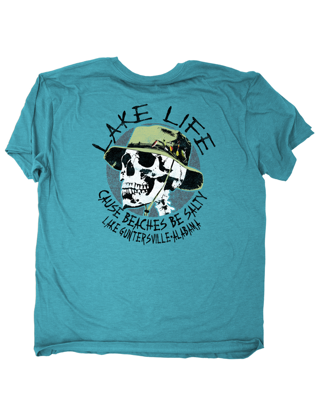 A turquoise blue short-sleeve t-shirt with a graphic print on the back. The graphic features a skull wearing a green hat, surrounded by the text 'LAKE LIFE CAUSE BEACHES BE SALTY' and 'LAKE GUNTERSVILLE, ALABAMA'.