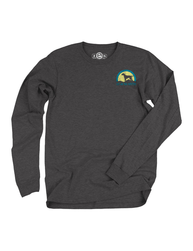 Dark grey long sleeve t-shirt with a graphic of a dog on a hill in front of a yellow and blue sunset with words Cast and Trail Outfitters.