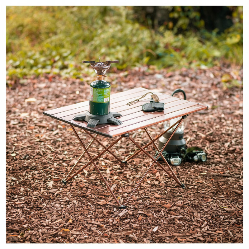 Small wooden camping table with a portable stove and other items on a natural outdoor background