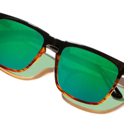 Black frame sunglasses with green reflective lenses and tortoise shell accents
