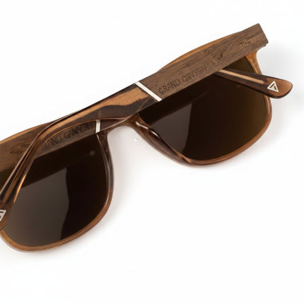 Close up of brown sunglasses with dark lenses and a wooden arm detail