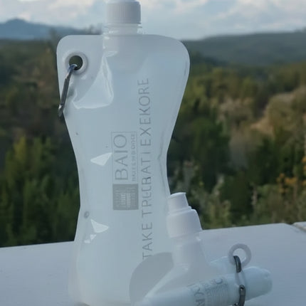 Two collapsible water bottles, one standing and one rolled, with a mountain landscape in the background