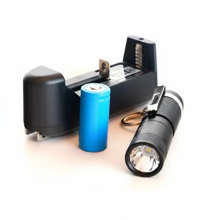 Black flashlight, blue battery, and black battery charger on a white background