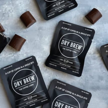 Dry Brew coffee sachets and chocolate squares on a light grey surface