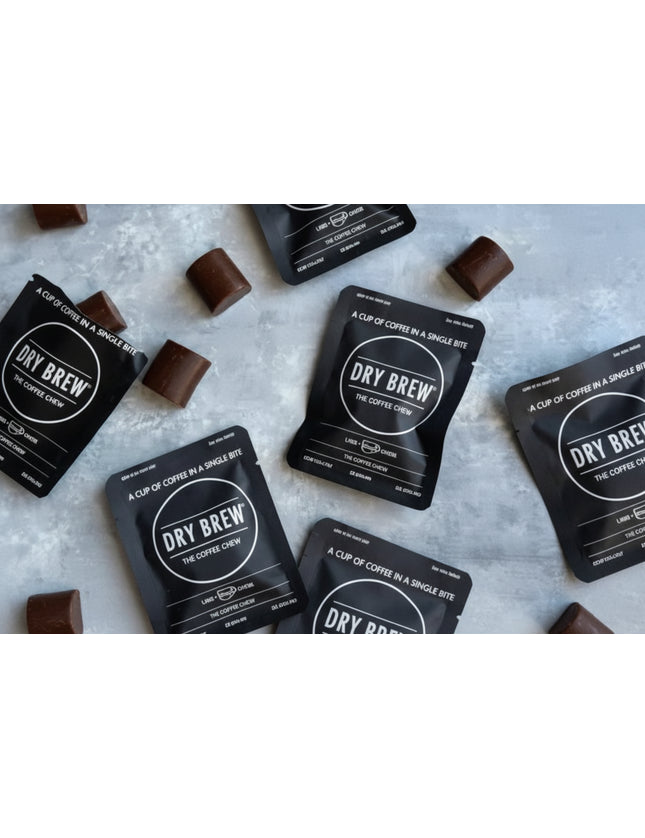 Dry Brew coffee sachets and chocolate squares on a light grey surface
