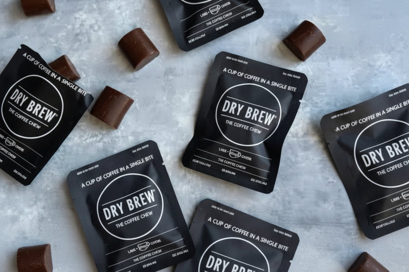 Dry Brew coffee sachets and chocolate squares on a light grey surface
