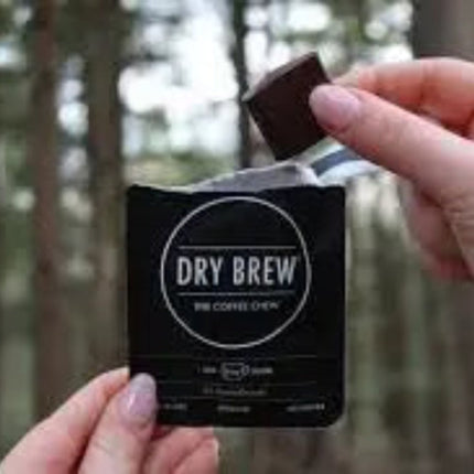 Hand holding a Dry Brew coffee chew packet, another hand placing a chocolate square into the packet