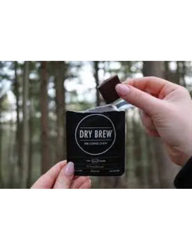 Hand holding a Dry Brew coffee chew packet, another hand placing a chocolate square into the packet