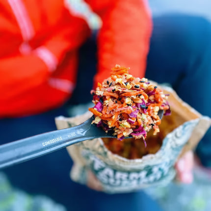 Close up of a spoon full of colorful granola being held over a pouch