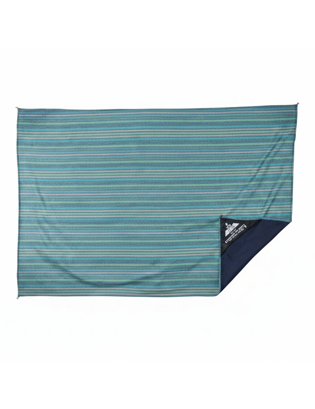 Blue and green striped beach blanket with a small black triangular logo in the bottom right corner