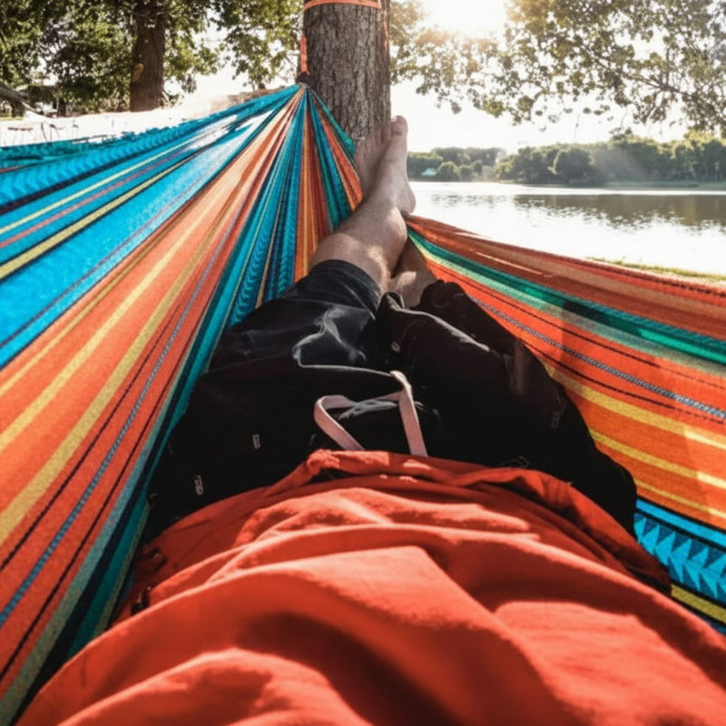 Person relaxing in a colorful hammock by a lake
