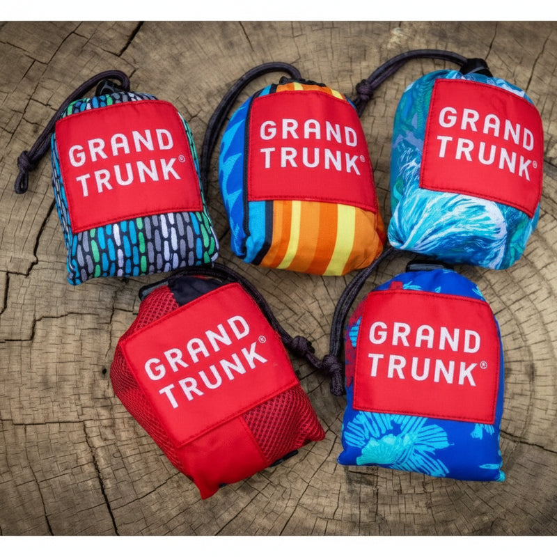 Five Grand Trunk hammocks in various colors and patterns, folded into their attached stuff sacks