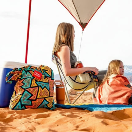 Woman and child sitting on a sandy beach under a sunshade