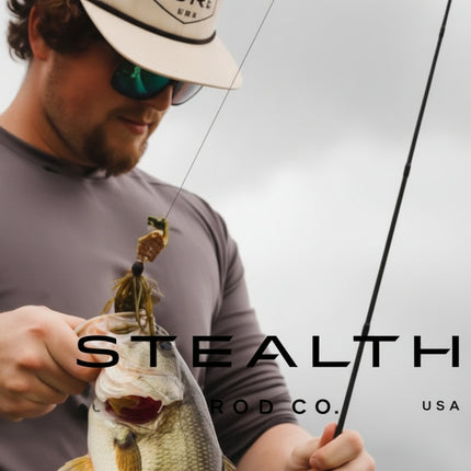 A man wearing a beige cap and sunglasses holds a largemouth bass while holding a fishing rod. The image features a dark gray overlay with the text 'STEALTH CO.