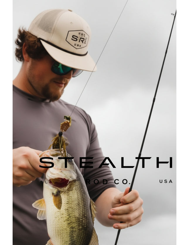 A man wearing a beige cap and sunglasses holds a largemouth bass while holding a fishing rod. The image features a dark gray overlay with the text 'STEALTH CO.