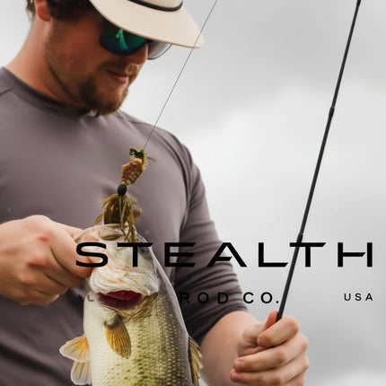 A man wearing a beige cap and sunglasses holds a largemouth bass while holding a fishing rod. The image features a dark gray overlay with the text 'STEALTH CO.