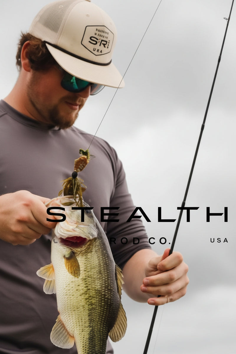 A man wearing a beige cap and sunglasses holds a largemouth bass while holding a fishing rod. The image features a dark gray overlay with the text 'STEALTH CO.