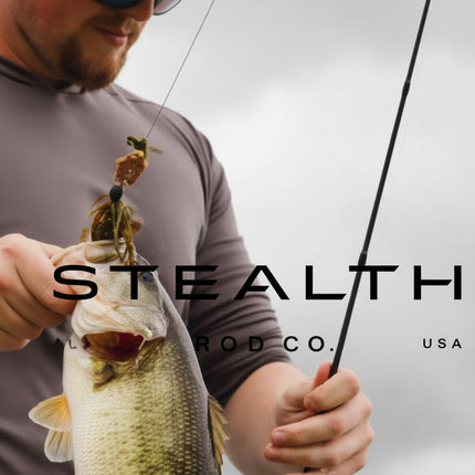 A man wearing a beige cap and sunglasses holds a largemouth bass while holding a fishing rod. The image features a dark gray overlay with the text 'STEALTH CO.