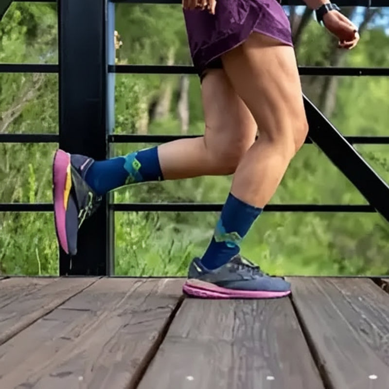 Person running on a wooden bridge, wearing purple shorts, blue socks, and grey and pink running shoes