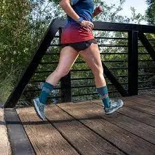 Woman running on a wooden bridge wearing blue and red athletic clothing and blue socks