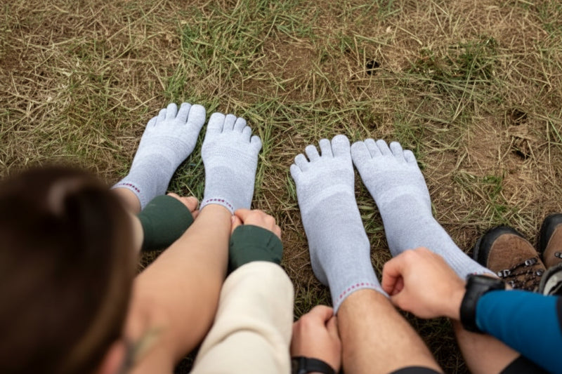 Two pairs of feet wearing grey toe socks on grass