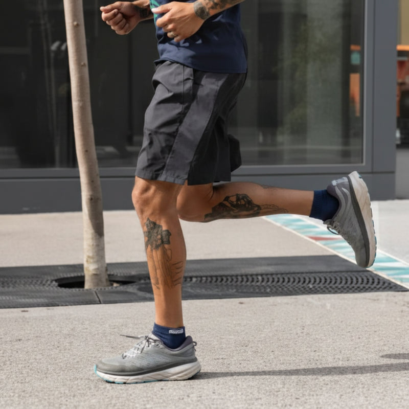 Person running in black shorts and grey athletic shoes