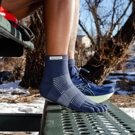 Person wearing blue toe socks and blue running shoes in a snowy outdoor setting