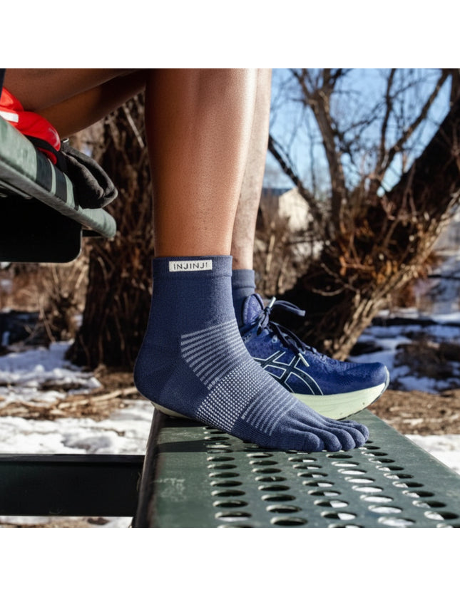 Person wearing blue toe socks and blue running shoes in a snowy outdoor setting
