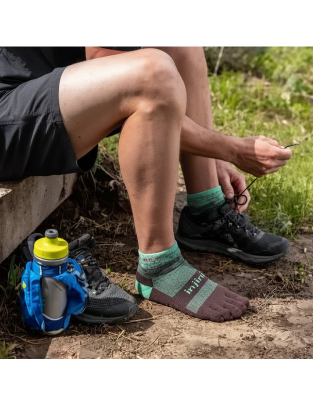 Person wearing green and brown toe socks and black trail running shoes, tying laces