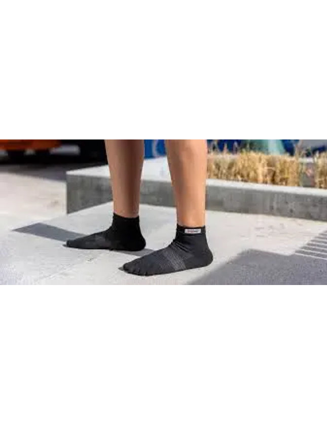 Person wearing black ankle socks with grey stripes on a concrete surface