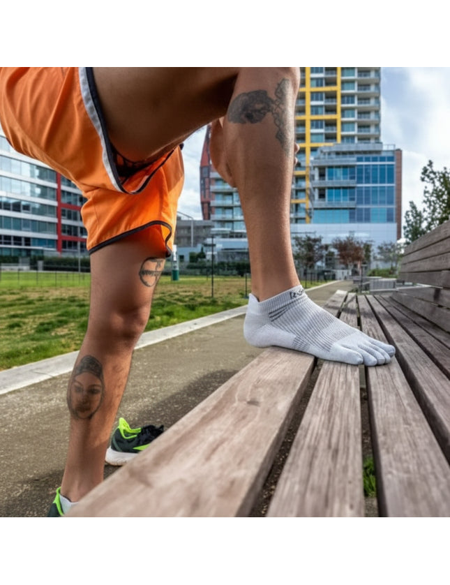 Man wearing white toe socks and orange shorts steps onto a wooden bench