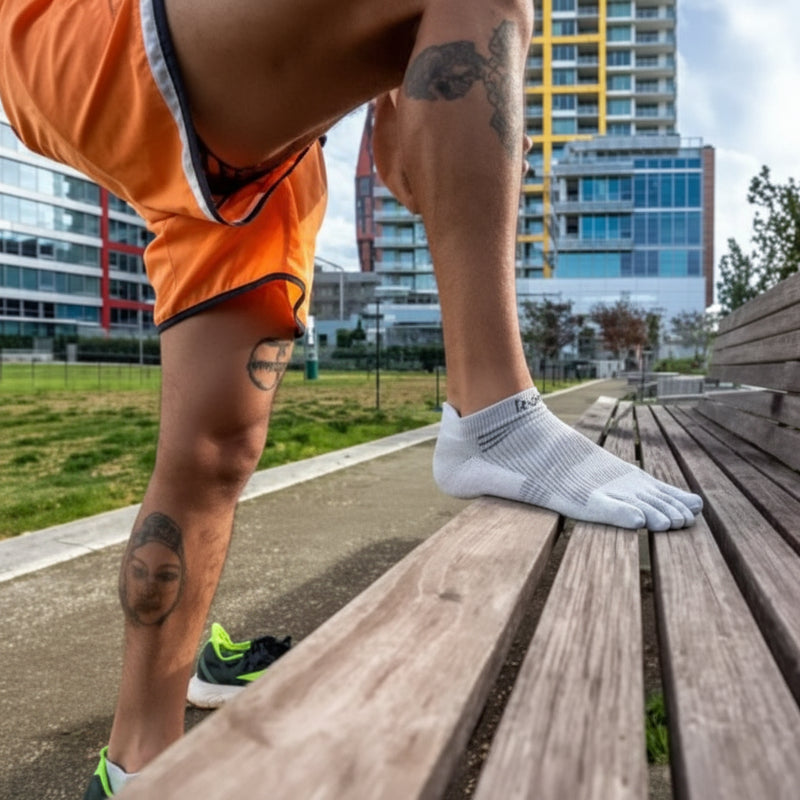 Man wearing white toe socks and orange shorts steps onto a wooden bench