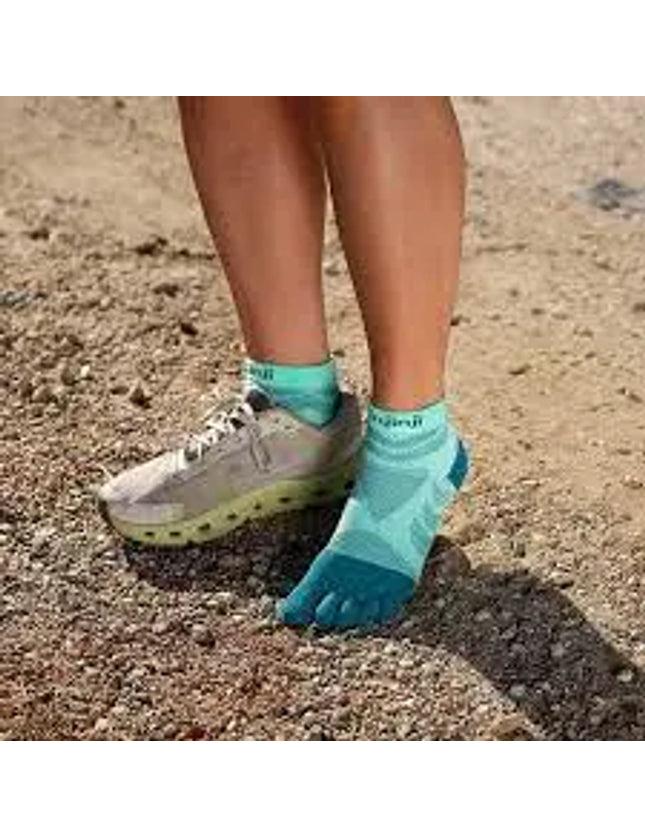 Person wearing turquoise toe socks and one running shoe on a dirt path