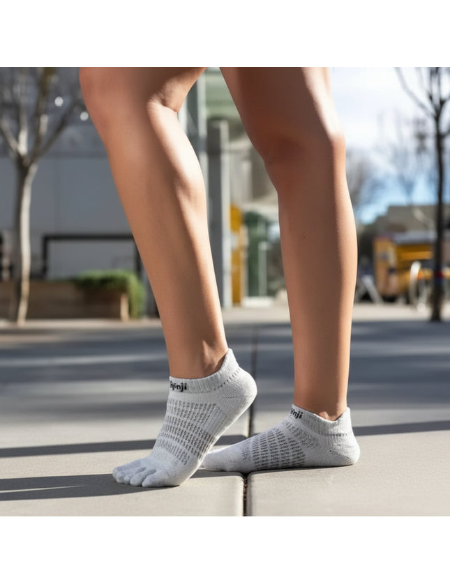 Person wearing light grey toe socks and standing on a sidewalk