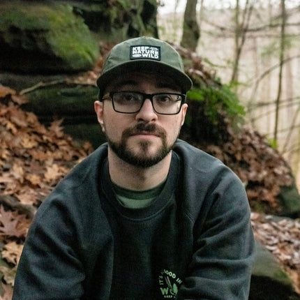 Man wearing a cap and glasses in a forest setting