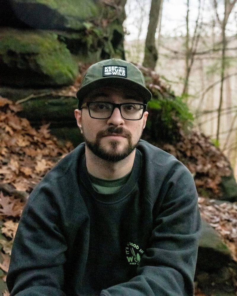Man wearing a cap and glasses in a forest setting
