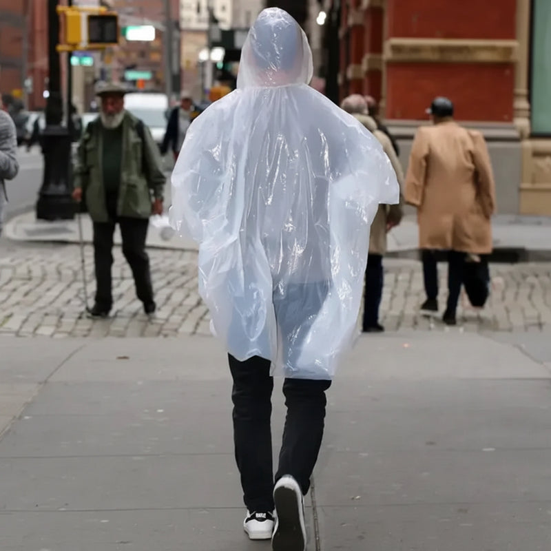 Person in a clear plastic poncho walking away on a city sidewalk