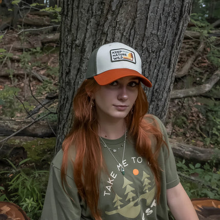 Woman with long red hair wearing a Keep Nature Wild hat and a Take Me To The Forest t-shirt