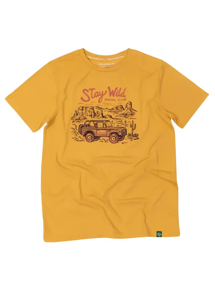 Mustard yellow t-shirt with a graphic of a desert landscape, an off-road vehicle, and Stay Wild Social Club text