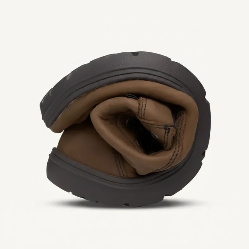 Brown leather shoe with a black sole, folded in half to show its flexibility